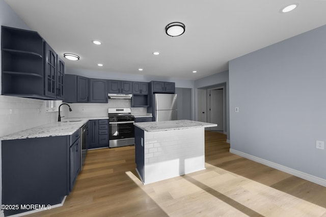 kitchen featuring backsplash, fridge, light wood-type flooring, stainless steel range oven, and a center island