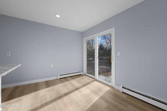 unfurnished room featuring a baseboard heating unit and light wood-type flooring