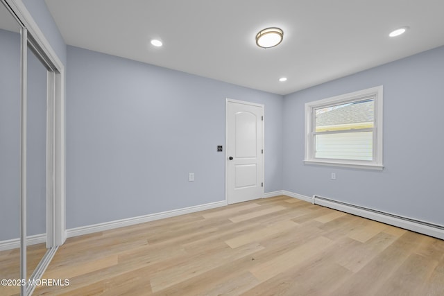 unfurnished bedroom with baseboard heating and light wood-type flooring