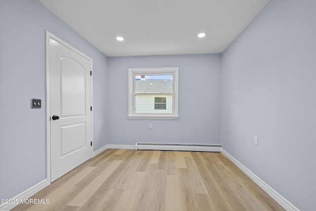 unfurnished room with a baseboard radiator and light wood-type flooring