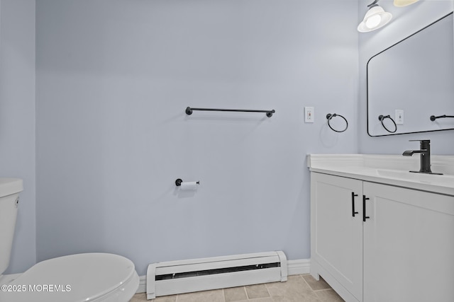 bathroom featuring toilet, vanity, a baseboard heating unit, and tile patterned floors