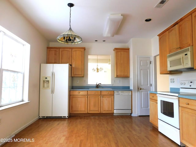 kitchen featuring white appliances, sink, hanging light fixtures, and light wood-type flooring