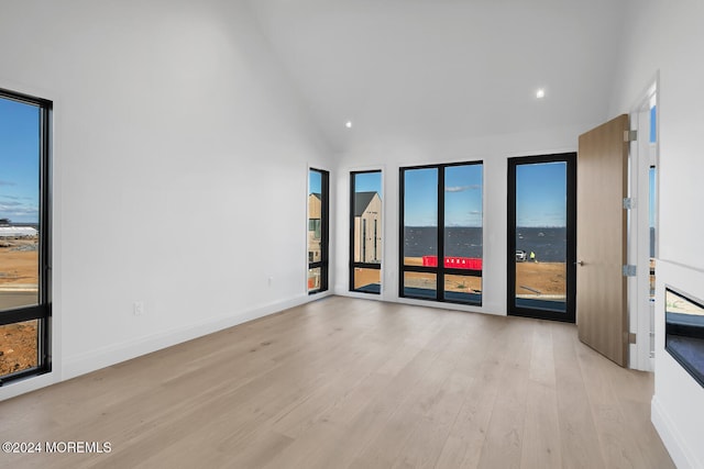 empty room with light hardwood / wood-style flooring, high vaulted ceiling, and a wealth of natural light