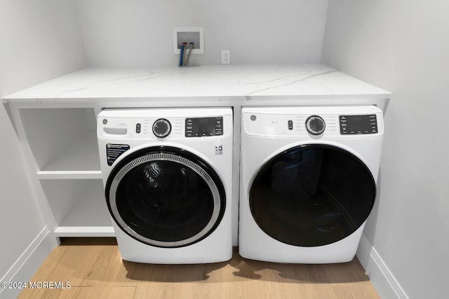 clothes washing area featuring light wood-type flooring and washer and clothes dryer