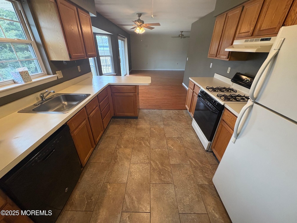 kitchen featuring black dishwasher, sink, white fridge, kitchen peninsula, and gas range