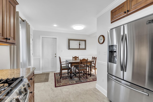 kitchen with stainless steel appliances, ornamental molding, and light stone countertops