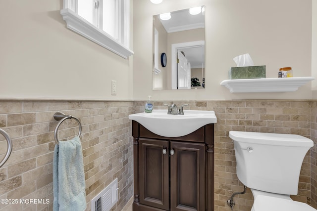 bathroom with toilet, vanity, and tile walls