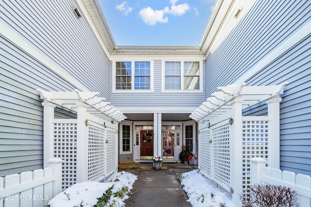 snow covered property entrance featuring a pergola