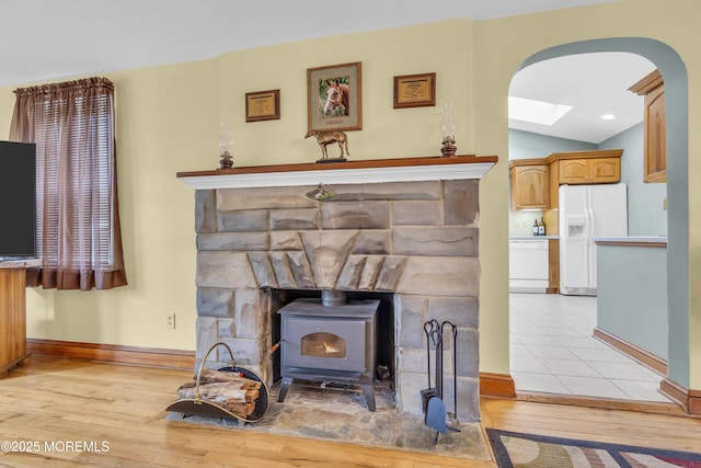 room details featuring a wood stove, white appliances, a skylight, and hardwood / wood-style floors