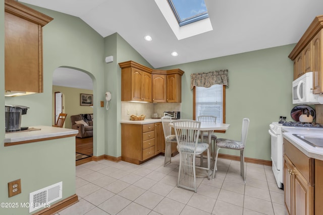 kitchen featuring light tile patterned floors, white appliances, decorative backsplash, and vaulted ceiling