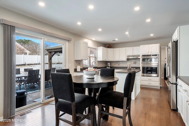 dining room with sink, a healthy amount of sunlight, and dark hardwood / wood-style flooring