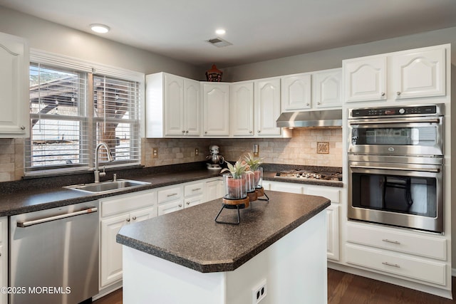 kitchen with white cabinets, a kitchen island, stainless steel appliances, tasteful backsplash, and sink