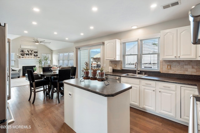 kitchen with sink, backsplash, white cabinets, and vaulted ceiling