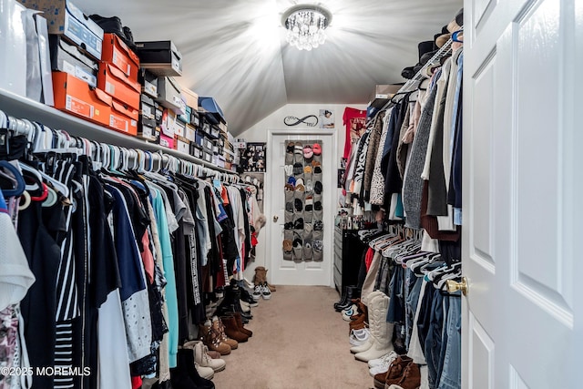 spacious closet featuring a notable chandelier, carpet, and lofted ceiling