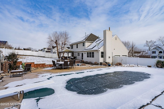 snow covered back of property with a gazebo