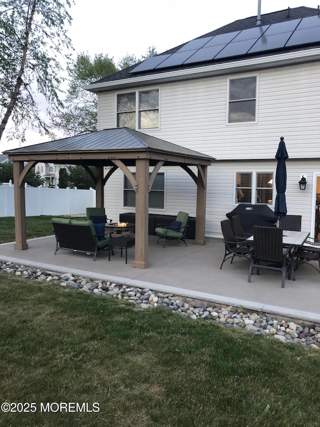 back of property featuring a lawn, a gazebo, solar panels, and a patio