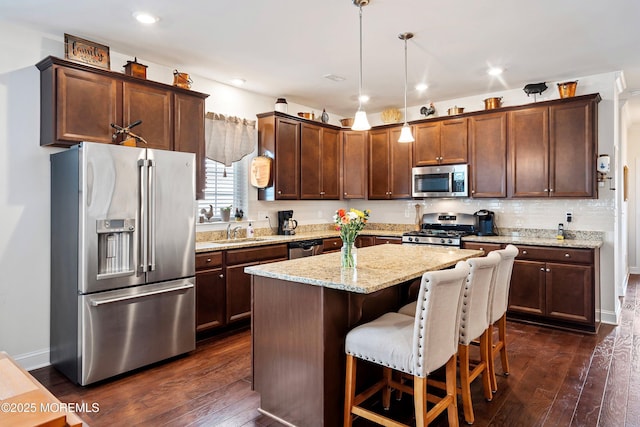 kitchen with a center island, decorative light fixtures, dark wood-type flooring, stainless steel appliances, and sink