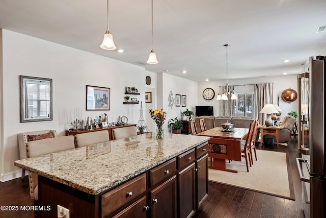 kitchen featuring light stone countertops, pendant lighting, high end refrigerator, and a kitchen island