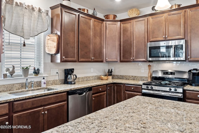 kitchen with sink, light stone countertops, and appliances with stainless steel finishes