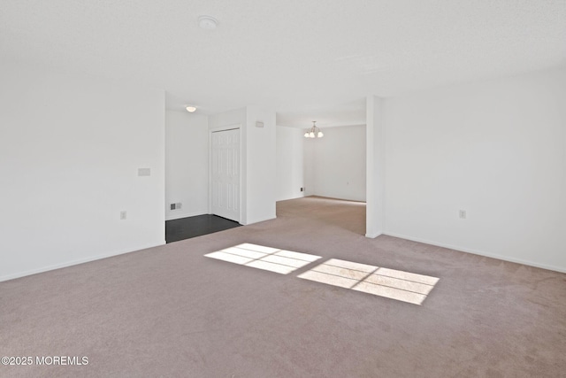 spare room featuring an inviting chandelier and carpet