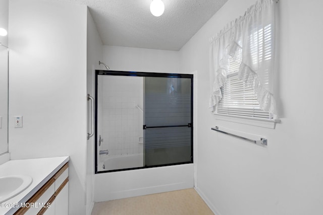 bathroom featuring enclosed tub / shower combo, vanity, and a textured ceiling