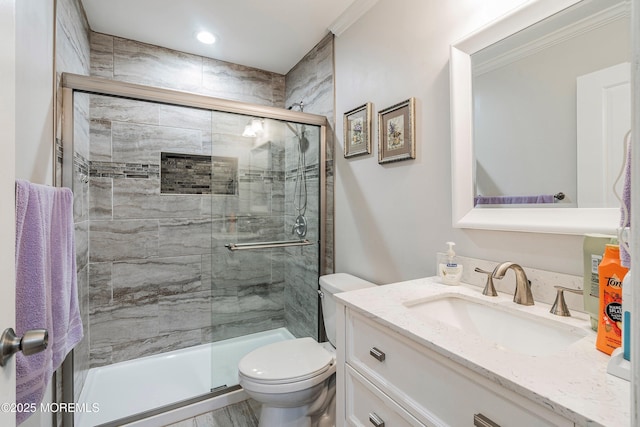 bathroom with ornamental molding, vanity, toilet, and a shower with door