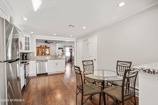 dining area with ornamental molding, sink, and dark wood-type flooring