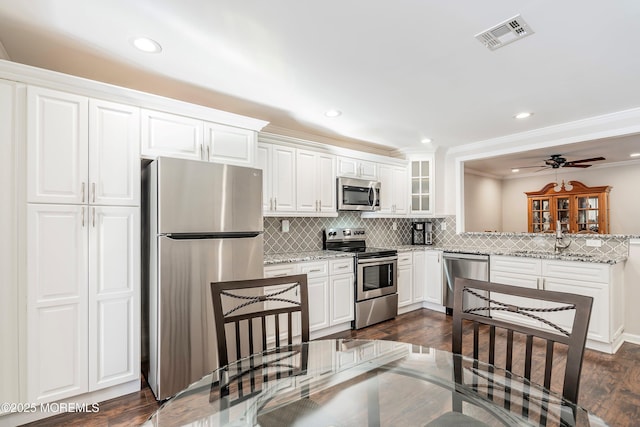 kitchen featuring light stone counters, tasteful backsplash, white cabinets, and appliances with stainless steel finishes