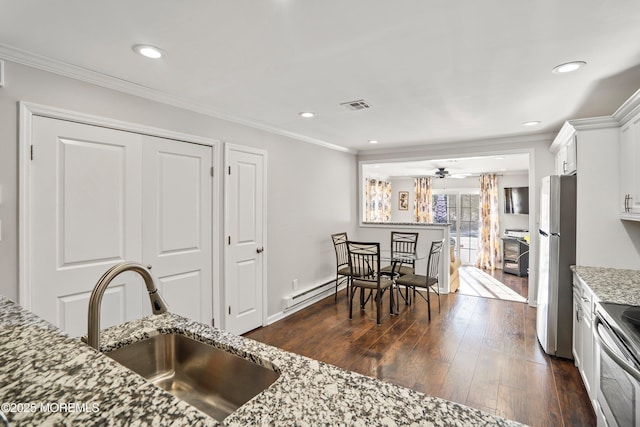 kitchen featuring sink, baseboard heating, appliances with stainless steel finishes, light stone countertops, and white cabinets