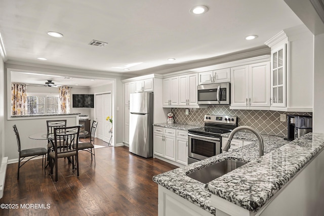 kitchen with sink, white cabinets, kitchen peninsula, stainless steel appliances, and light stone countertops