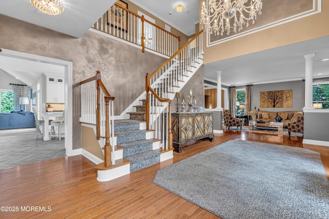 interior space with crown molding, hardwood / wood-style flooring, a wealth of natural light, and ornate columns