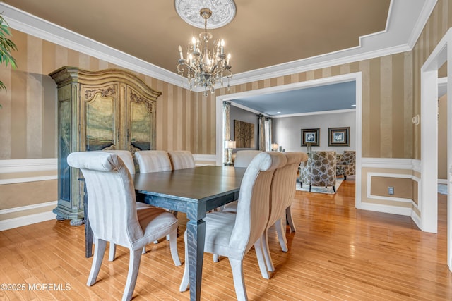 dining area with an inviting chandelier, light hardwood / wood-style flooring, and ornamental molding