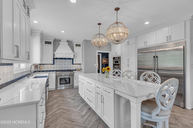 kitchen with a kitchen island, premium appliances, decorative light fixtures, and custom range hood