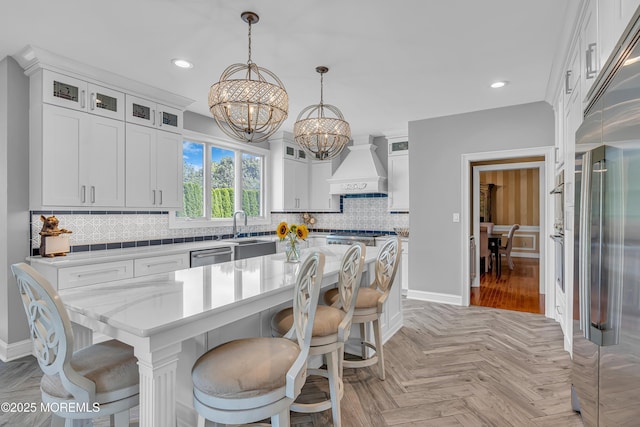 kitchen with white cabinets, a center island, appliances with stainless steel finishes, premium range hood, and hanging light fixtures