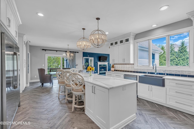 kitchen featuring white cabinetry, a center island, stainless steel appliances, and an inviting chandelier