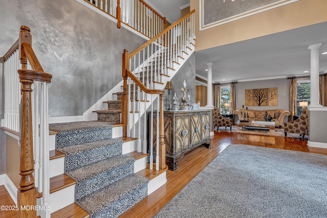 stairs featuring decorative columns, hardwood / wood-style flooring, and crown molding