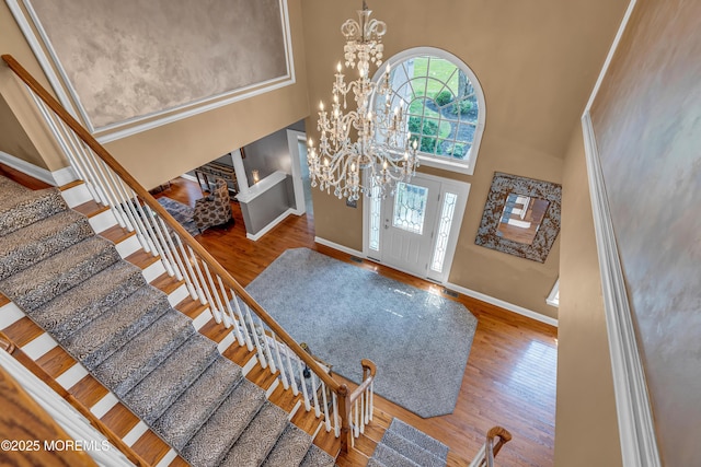 foyer entrance with a towering ceiling, an inviting chandelier, and hardwood / wood-style flooring