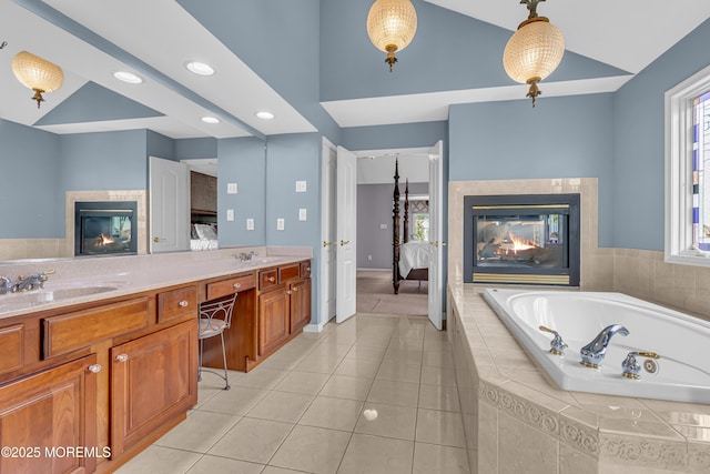 bathroom with a multi sided fireplace, tiled bath, tile patterned floors, vanity, and vaulted ceiling