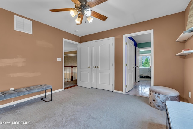 interior space featuring light carpet, a closet, ensuite bath, and ceiling fan