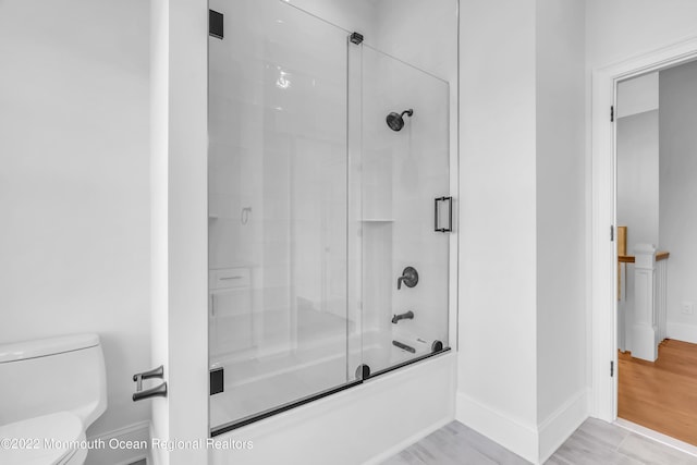 bathroom featuring toilet and combined bath / shower with glass door