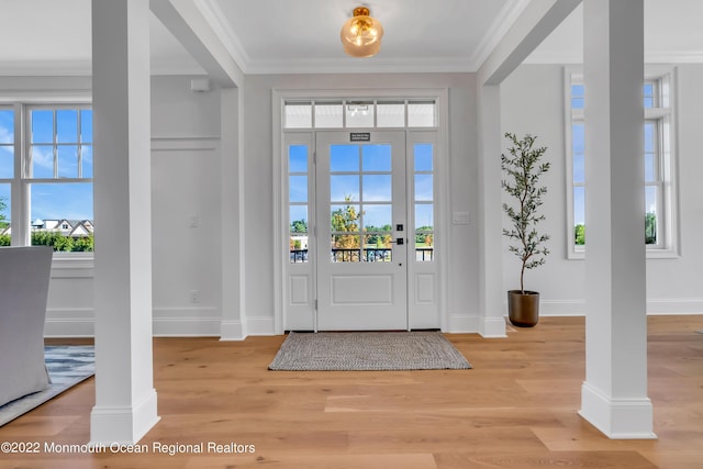 entrance foyer featuring crown molding, light hardwood / wood-style floors, and ornate columns