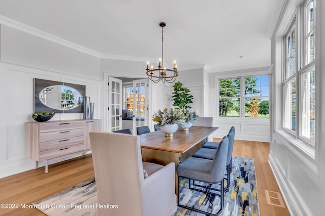 dining area with crown molding, an inviting chandelier, and light hardwood / wood-style floors