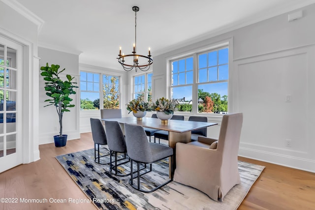 dining area with ornamental molding, a chandelier, and light hardwood / wood-style flooring