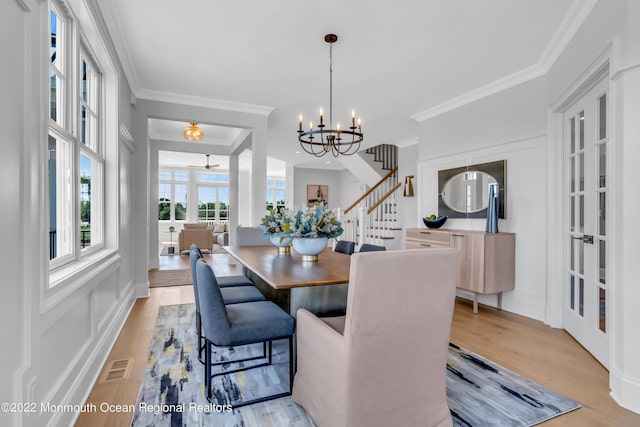 dining area featuring an inviting chandelier, crown molding, and light hardwood / wood-style flooring