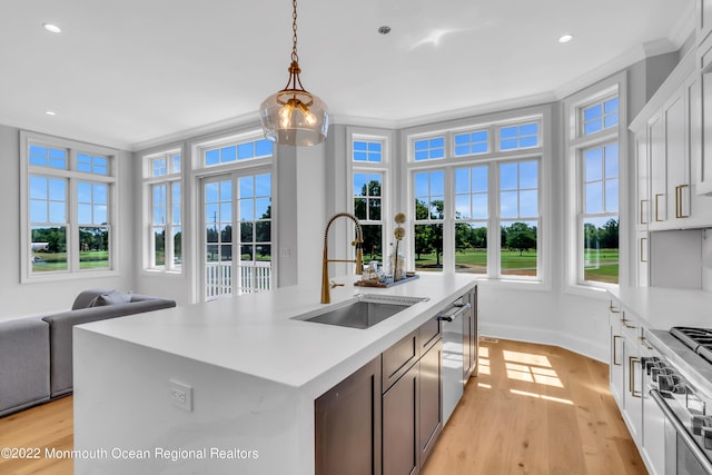 kitchen featuring a kitchen island with sink, sink, pendant lighting, and white cabinets