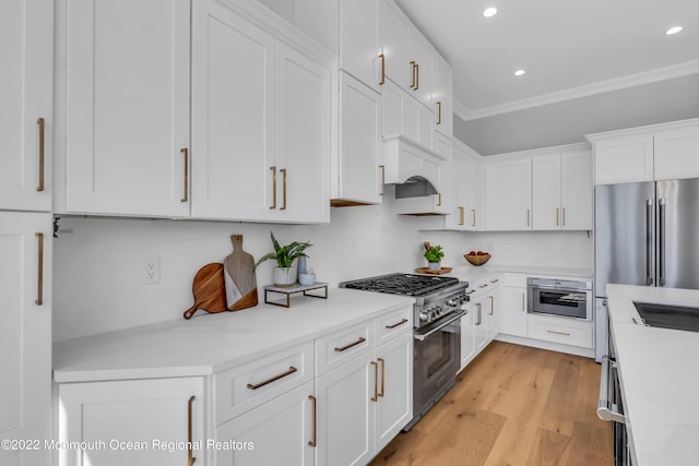 kitchen featuring crown molding, white cabinetry, light stone counters, premium appliances, and light hardwood / wood-style floors