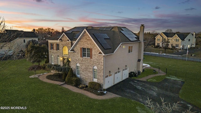 exterior space with central AC, a garage, a lawn, and solar panels