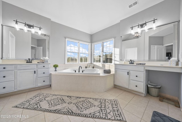 bathroom featuring tile patterned flooring, vanity, and tiled bath