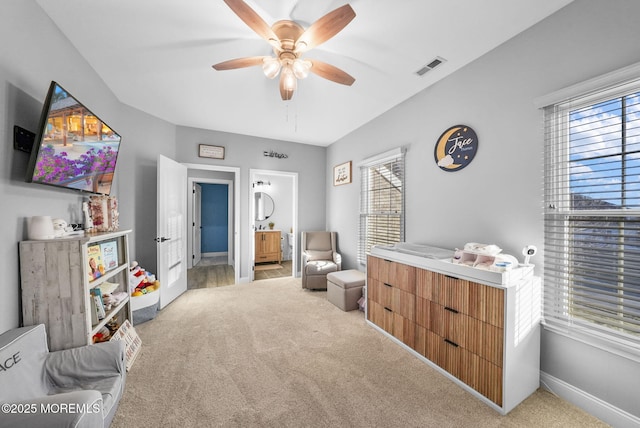 bedroom featuring connected bathroom, light colored carpet, and ceiling fan