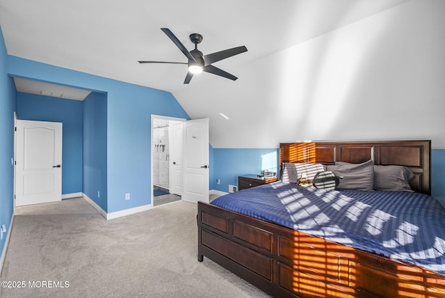 carpeted bedroom with connected bathroom, vaulted ceiling, and ceiling fan